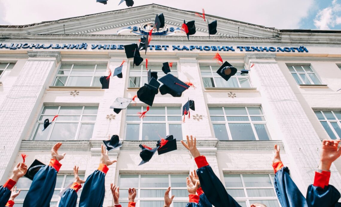 group of fresh graduates students throwing their academic hat in the air